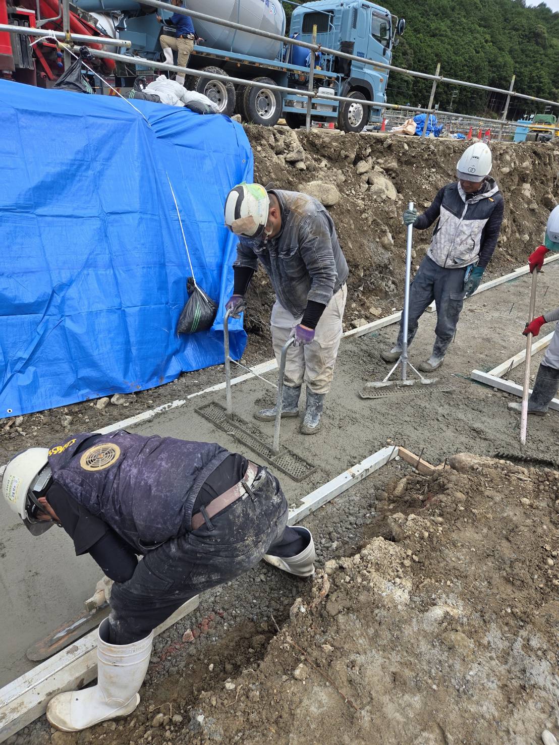 複数の作業員が連携してコンクリートを均す土木工事の作業風景